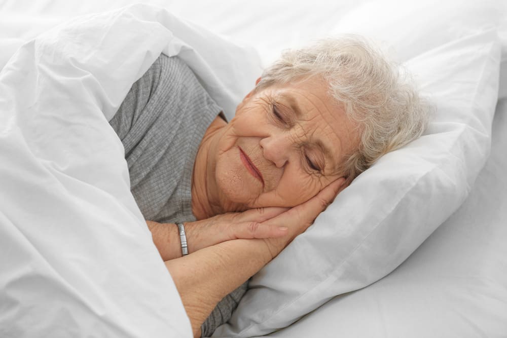 Una mujer mayor durmiendo plácidamente en su cama. 