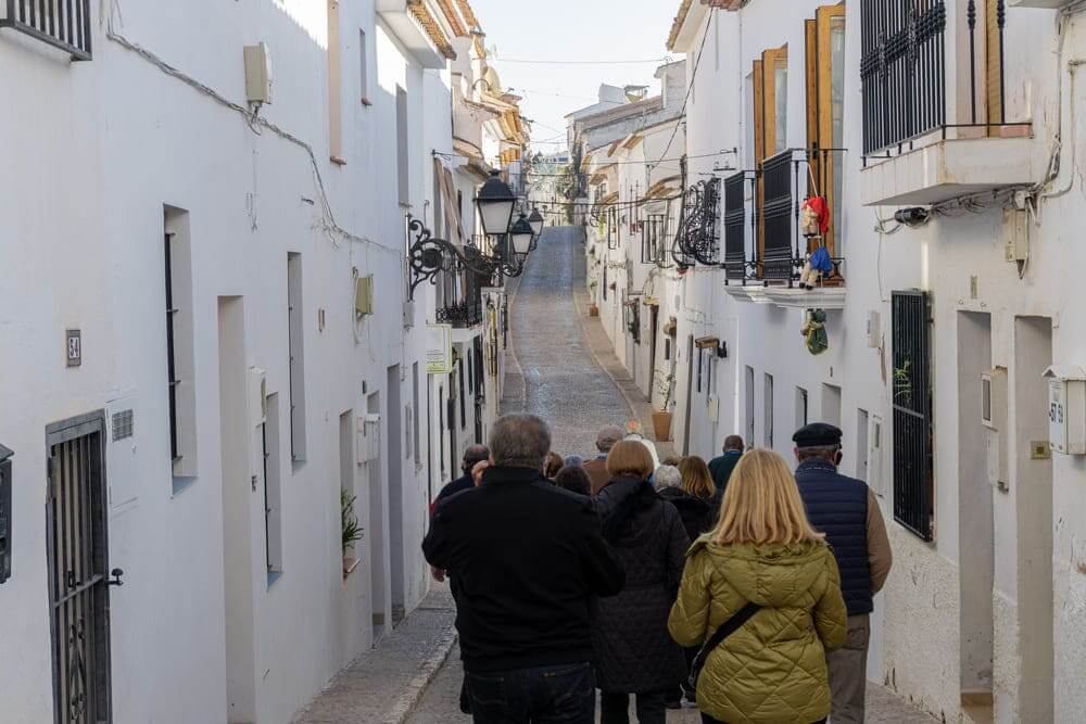 Un grupo de ancianos pasean por una calle de un pueblo español. 