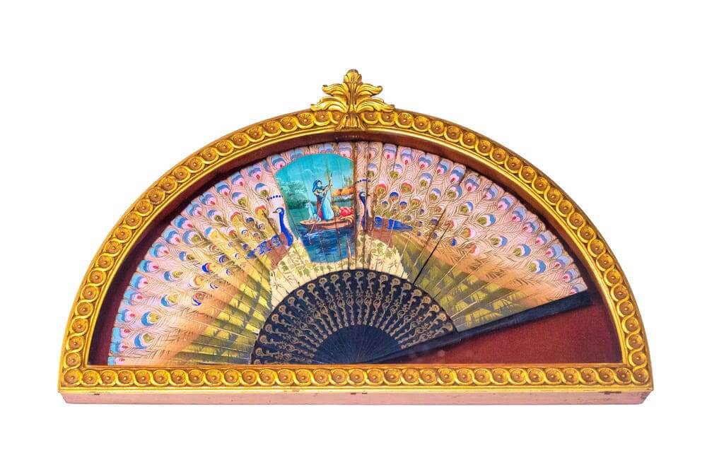Un abanico decorado con adornos egipcios y el marco de oro. 