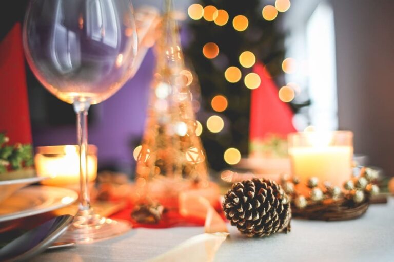 Una mesa con una copa de vino y adornos navideños.