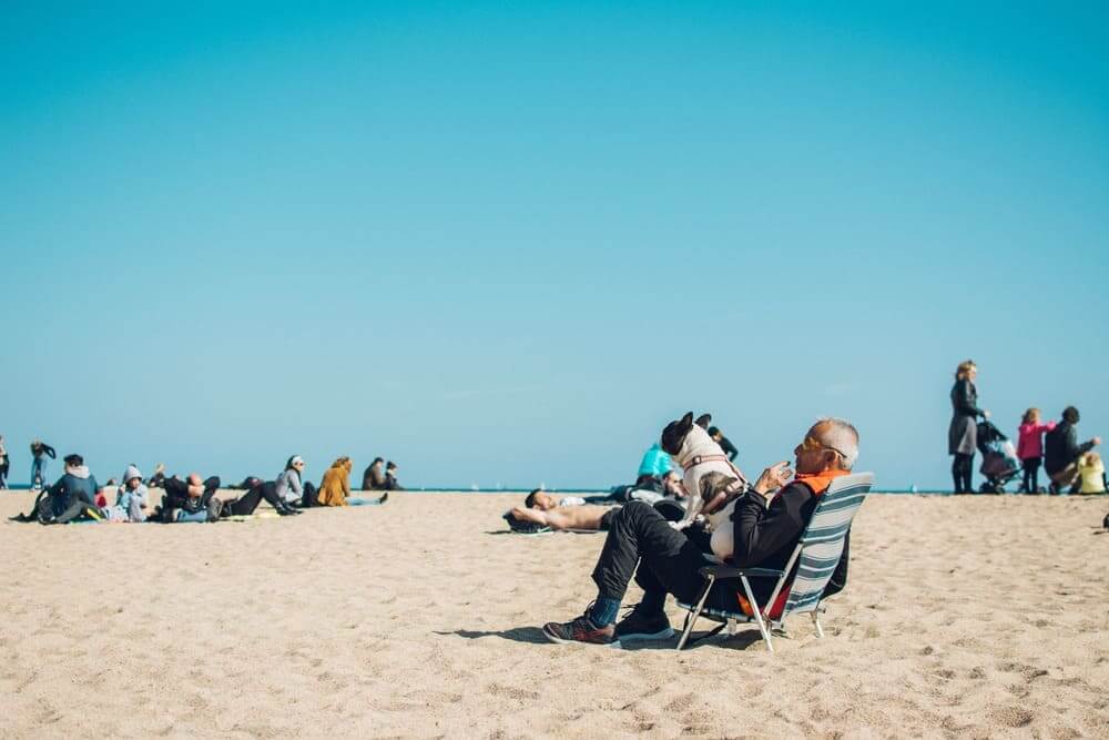 Un señor mayor sentado en una hamaca en la arena de la playa. 