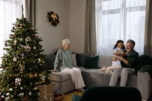 Dos ancianos con su nieta en el salón de su casa y con el árbol de Navidad.