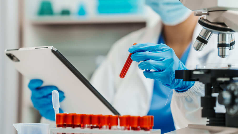 Un científico en un laboratorio haciendo pruebas con probetas de sangre. 
