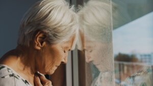 Mujer mayor maltratada apoya la cabeza en la ventana mientras cierra los ojos