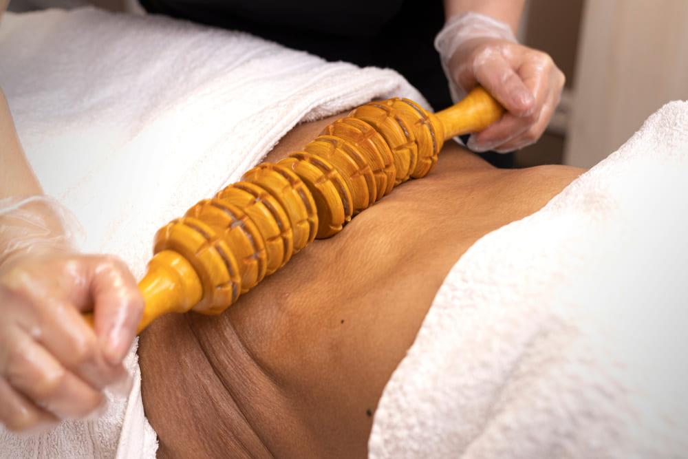 Un rodillo de madera siendo masajeado por la espalda de una persona. 