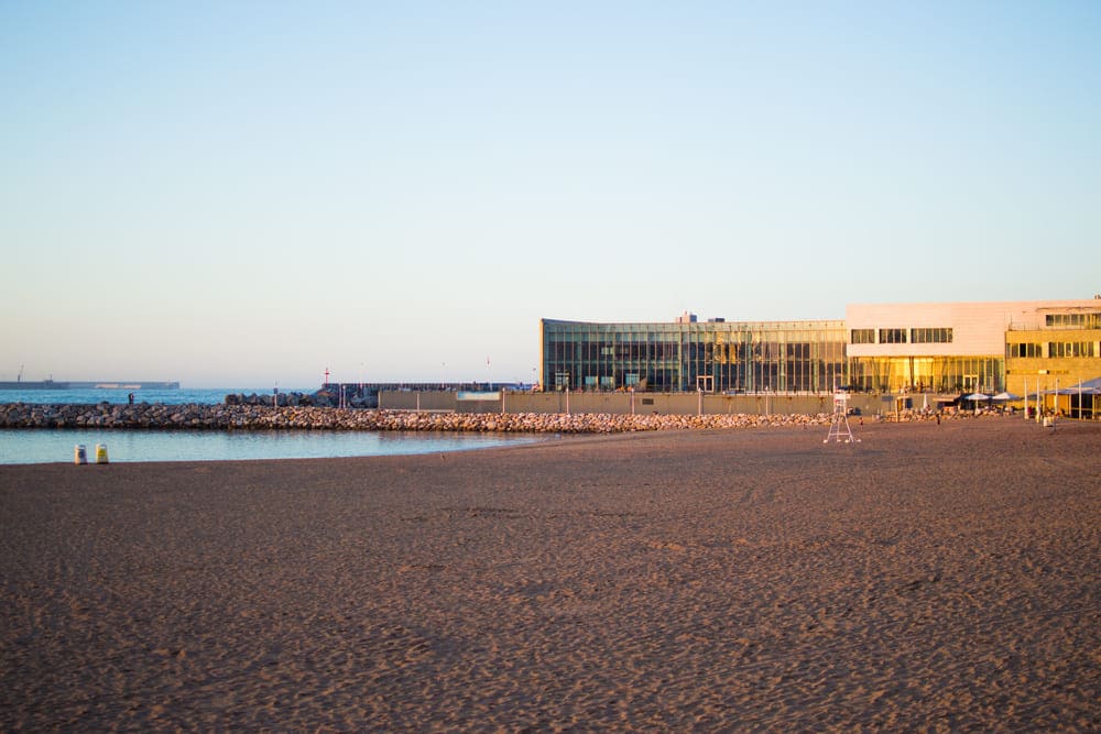 Una visión panorámica de la Playa de Poniente, en Gijón, con el ocaso del sol. 