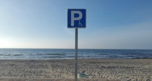 Una playa española con una señal de parking adaptado a personas con problemas de movilidad.