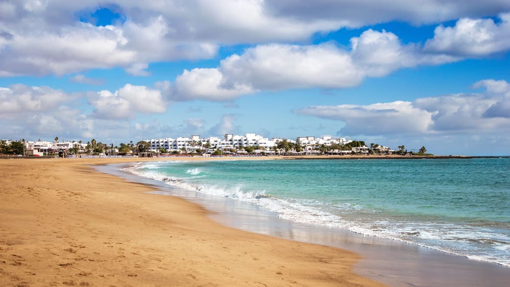 Una vista panorámica de la playa de Los Pocillos en Lanzarote, a plena luz del día. 
