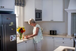 Una señora mayor en su cocina junto a su nevera.