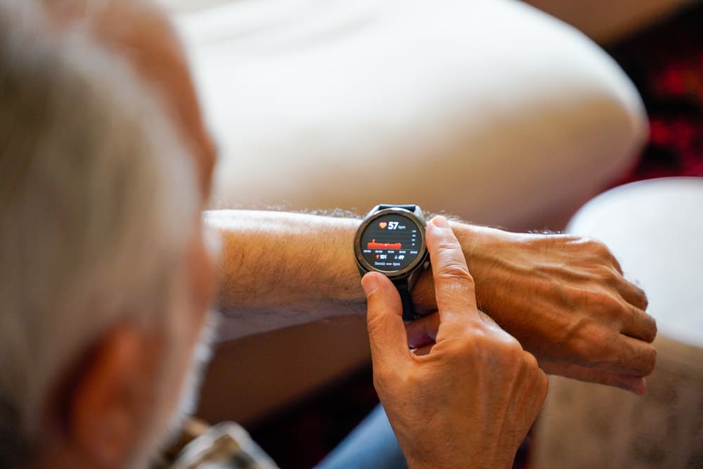 Un señor mayor mira su reloj de muñeca y ajusta la hora. 