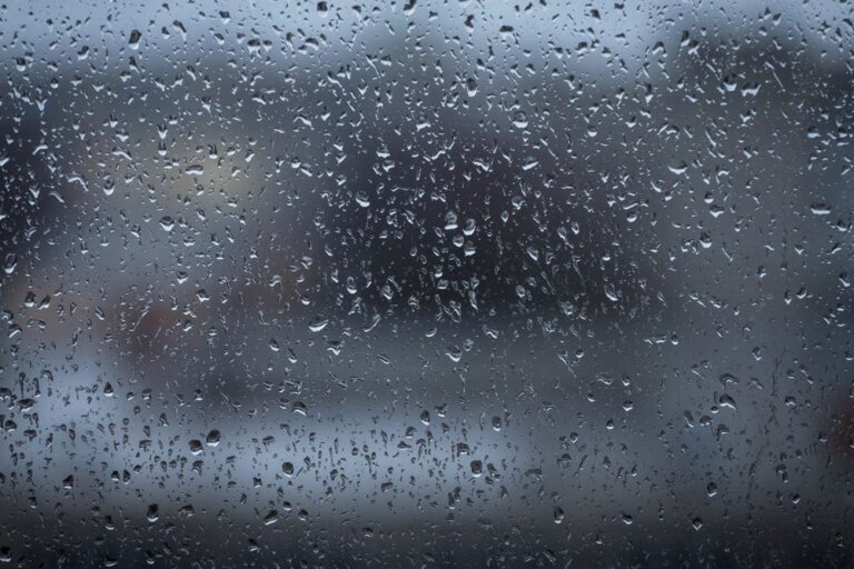 Una imagen de una ventana de una casa con gotas de agua ante la lluvia del exterior.