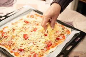 Un plano de una mano de un anciano sujetando una pizza.