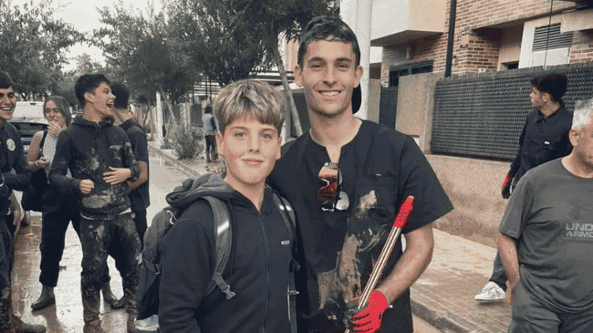 Un niño aficionado del Valencia CF se hace una foto con un jugador del club, Hugo Duro, mientras limpian las calles de un municipio afectado por la DANA. 