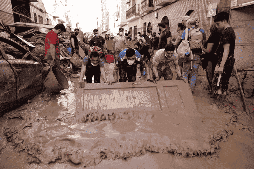 Un grupo de jóvenes achican agua del suelo con una superficie tras las inundaciones en Valencia por la DANA. 