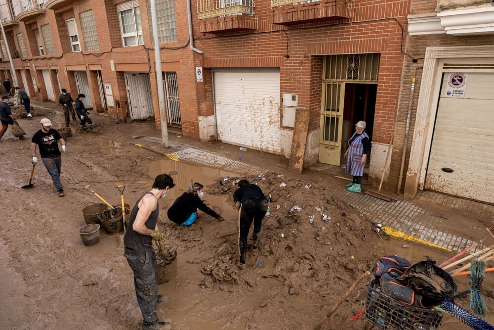 Vecinos ayudan a limpiar un bajo de un municipio afectado por la DANA en condiciones insalubres. 