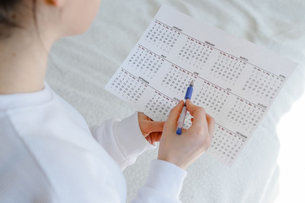 Una chica con un calendario y un bolígrafo para apuntar fechas señaladas. 