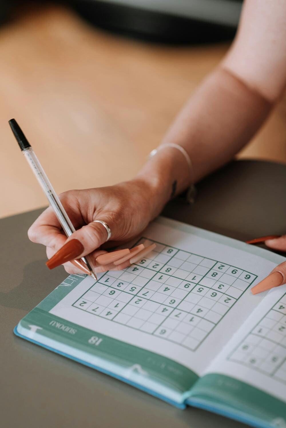 Una señora con un bolígrado descifrando números del sudoku. 