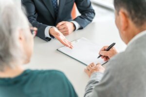 Una firma de documentos entre una mujer mayor, un chico joven y un notario.
