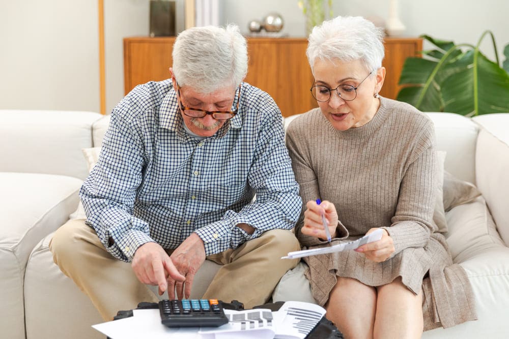 Una pareja de ancianos calculando unos datos en la calculadora. 