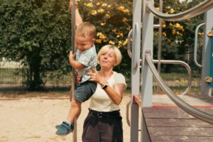 Una abuela ayuda a su nieto a montarse en una atracción fija de u parque.
