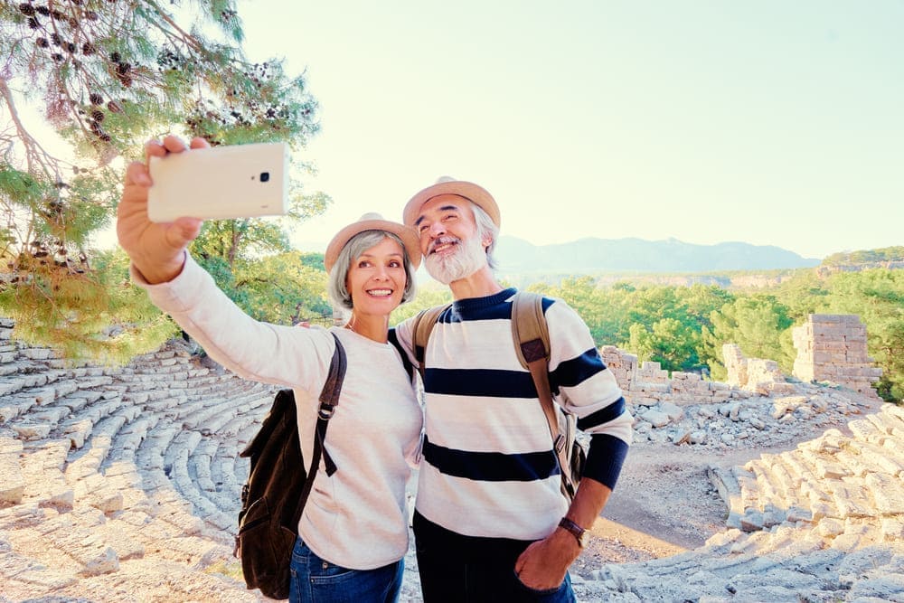 Una pareja de ancianos se hace un selfie en un viaje a unas ruinas al aire libre. 