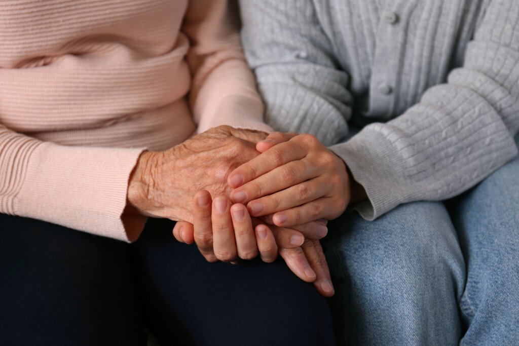 manos entrelazadas de madre anciana e hija 