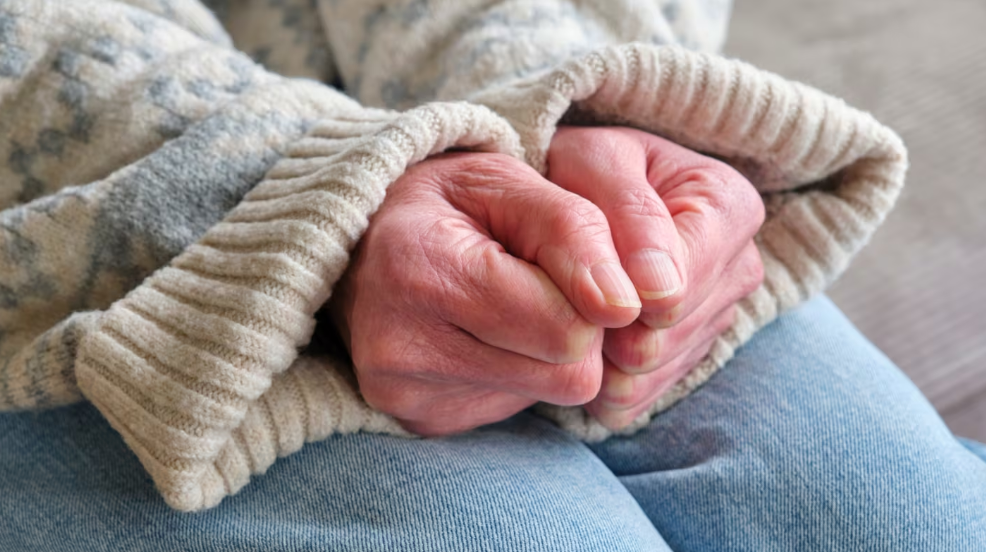 manos de persona mayor con jersey de punto apretando los puños por el frío 