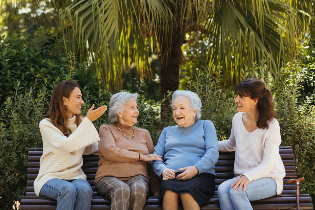 Curso auxiliar de geriatría señoras mayores acompañadas de sus cuidadoras en un banco del parque