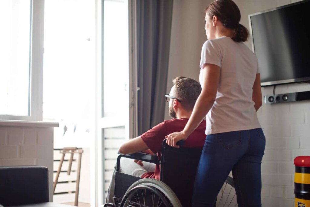 hombre sentado en sillade ruedas y mujer empujando