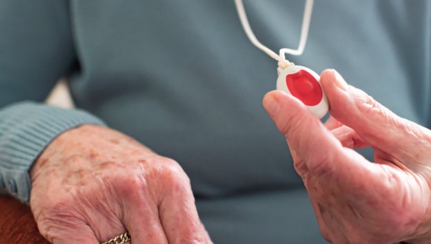 dispositivo de teleasistencia mujer mayor sujetando el dispositivo de teleasistencia (botón rojo colgado) para personas mayores