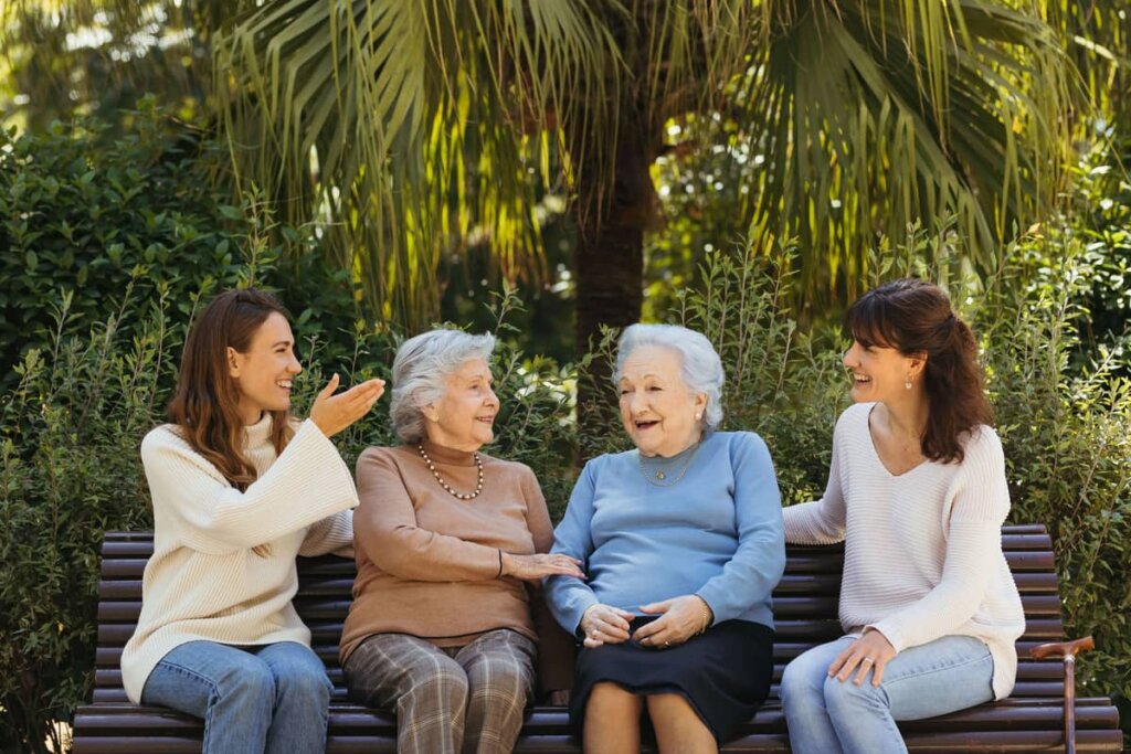 mujers mayores y jovenes sentadas en el banco del jardin