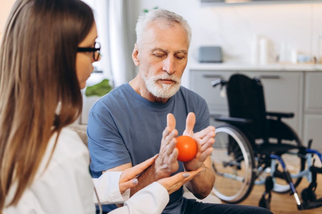 Rehabilitación ictus persona mayor Persona mayor realizando con una pelota bajo supervisión de una fisio ejercicios de rehabilitación