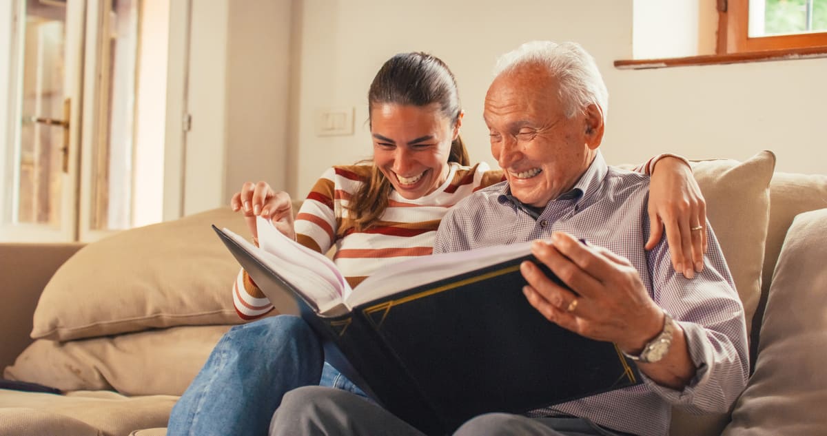 Día del Padre Padre e hija mirando recuerdos de forma alegre en un álbum de fotos.