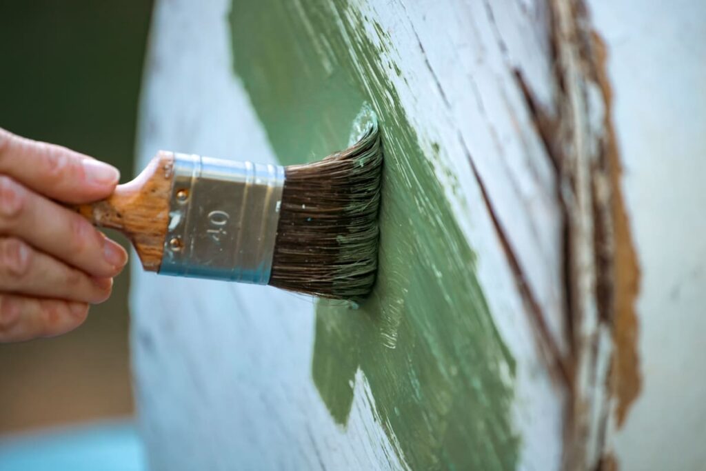 actividades para personas con Alzheimer Manos de persona mayor sosteniendo una brocha y pintando de verde una mueble