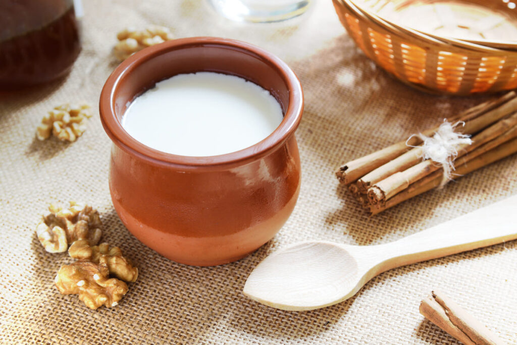 Meriendas de los abuelos Cuajada de miél en vaso de barro, en el salvamanteles a modo de decoración nueces, cuchara de madera, canela y cesta de mimbre