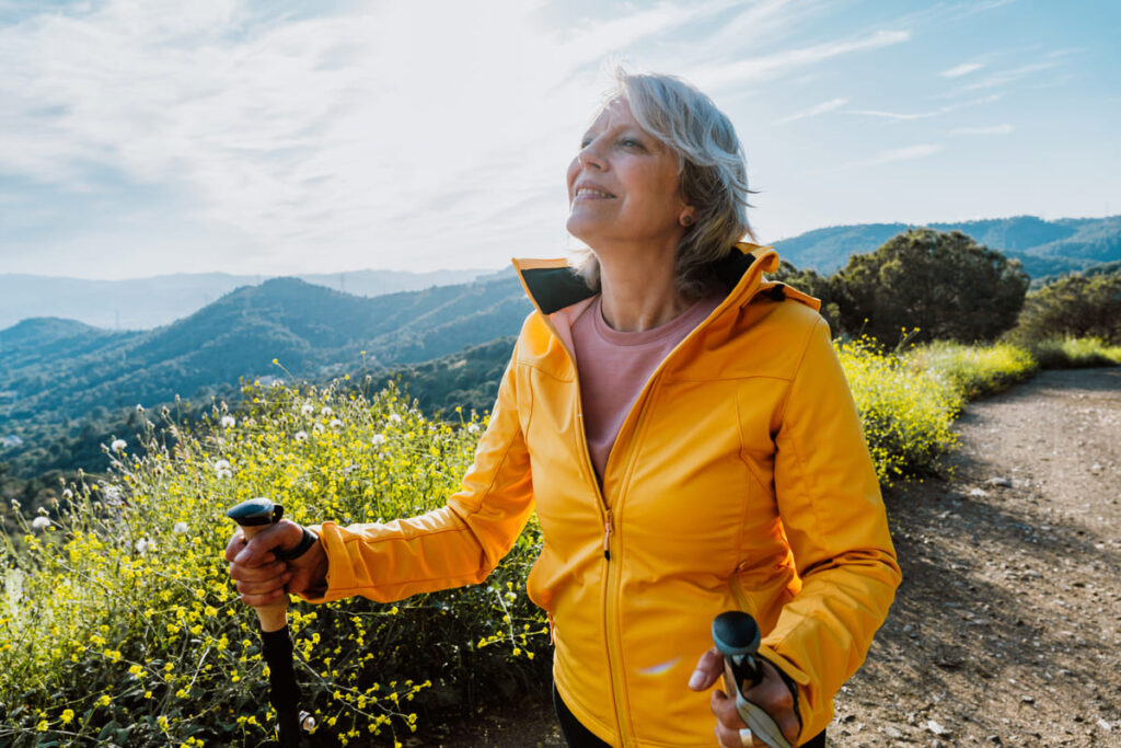 actividades para personas con Alzheimer Mujer adulta en un paisaje de montaña realizando actividad física de caminar al aire libre.