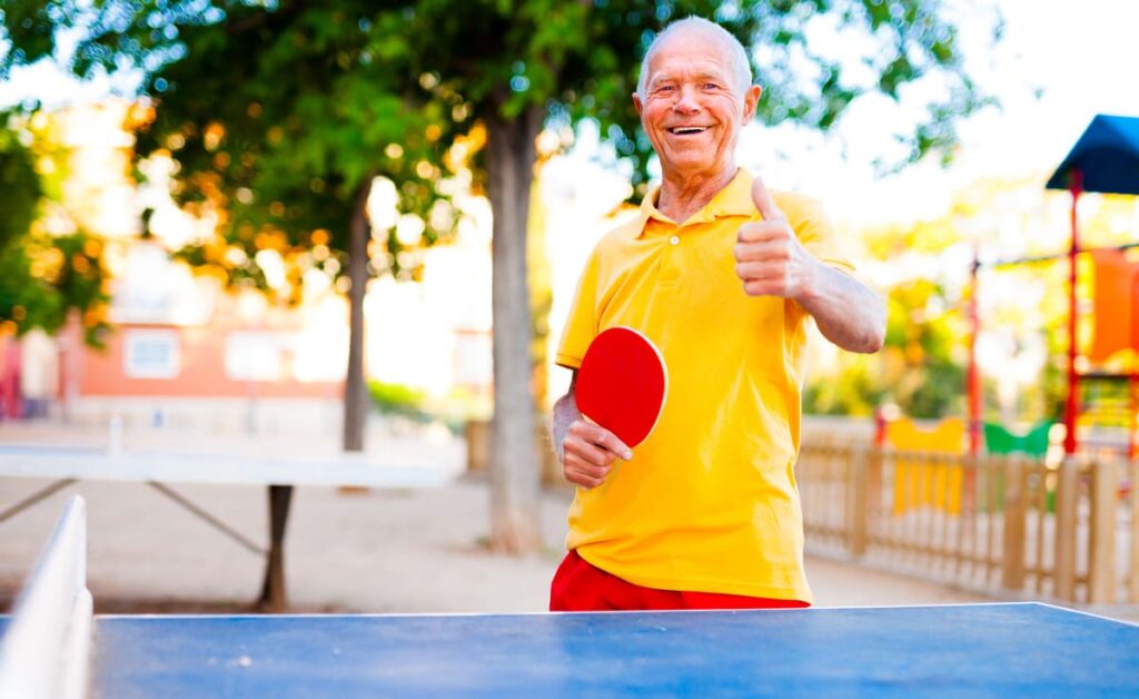 Deporte en personas mayores hombre mayor alegre en el parque jugando al ping pong
