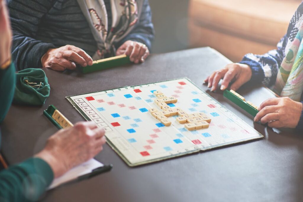 Juegos de mesa para personas con demencia los brazos y manos de personas mayores jugando a scrabble sobre una mesa