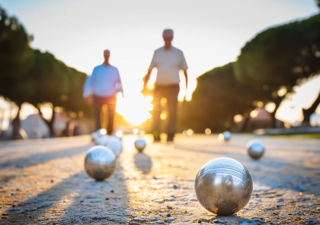 Deporte en personas mayores Dos ancianos de fondo en segundo plano difuminado jugando en un parque a la petanca y en primer plano las bolas metálicas de petanca